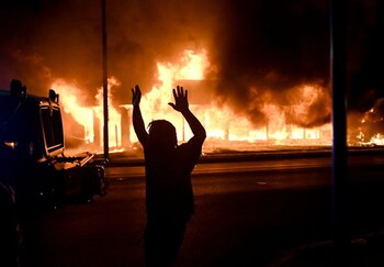 IMAGEN DE ARCHIVO. Un hombre camina con sus brazos en alto junto a un vehículo blindado mientras arden una oficinas tras las manifestaciones luego de que un policía disparara a un hombre negro en Kenosha, Wisconsin, EEUU, Agosto 24, 2020. REUTERS/Stephen Maturen