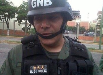 Un hombre porta un casco militar con las letras GNB y un chaleco táctico con la inscripción R. Quero S
