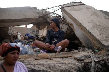 Fabiana Jaimes está sentada junto a un edificio derrumbado por los terremotos mientras espera a que los trabajadores terminen de retirar los escombros en la búsqueda incesante de su madre, Yalizca Bravo, en La Guaira, Venezuela, el jueves 23 de julio de 2026
(Foto AP/Ariana Cubillos)