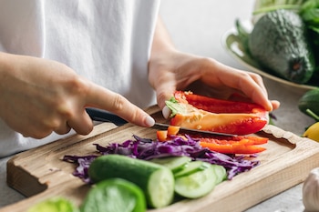 Una mujer cortando varias verduras (Magnific)
