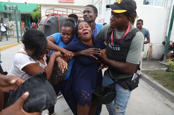 La esposa de un periodista, que fue baleado en un ataque de una banda armada al Hospital General, llora mientras una ambulancia llega con su cuerpo a otro hospital de Puerto Príncipe, Haití, el 24 de diciembre de 2024 (AP Foto/Odelyn Joseph)