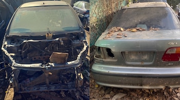 Parte frontal de un automóvil desmantelado con el motor expuesto, junto a la parte trasera de un Honda Civic de color gris cubierto de polvo y hojas secas.