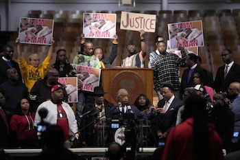 Multitud de personas en un auditorio. Un hombre en un podio con micrófonos, y otros levantando pancartas que dicen 'I AM A MAN' con la foto de un hombre herido y una que dice 'JUSTICE'