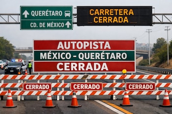 Primer plano de barreras de tráfico, conos y letreros que indican "AUTOPISTA MÉXICO-QUERÉTARO CERRADA" bajo un cartel electrónico y señales de dirección.