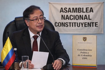 Gustavo Petro, con gafas, hablando en un podio. Detrás de él, una bandera de Colombia, la Constitución de 1991 y un cartel de "Asamblea Nacional Constituyente".