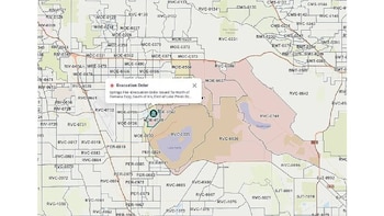 Un mapa digital muestra áreas geográficas con códigos alfanuméricos y zonas sombreadas en beige que indican órdenes de evacuación por un incendio