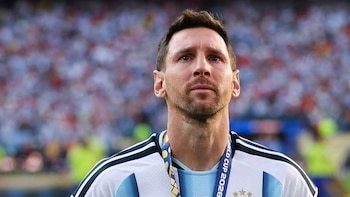 Primer plano de Lionel Messi con camiseta de Argentina, medalla FIFA World Cup 2026, tatuajes en brazo izquierdo y público borroso de fondo