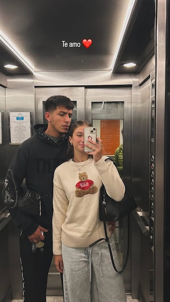 Indiana Cubero y Thiago Silvero se toman una selfie en un ascensor. Ella usa un suéter claro con un oso. Él, una sudadera oscura. En la pared se lee 'Te amo'