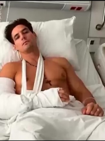 Facundo Gonzalez acostado en una cama de hospital, con el torso descubierto, el brazo izquierdo vendado y sostenido por un cabestrillo blanco