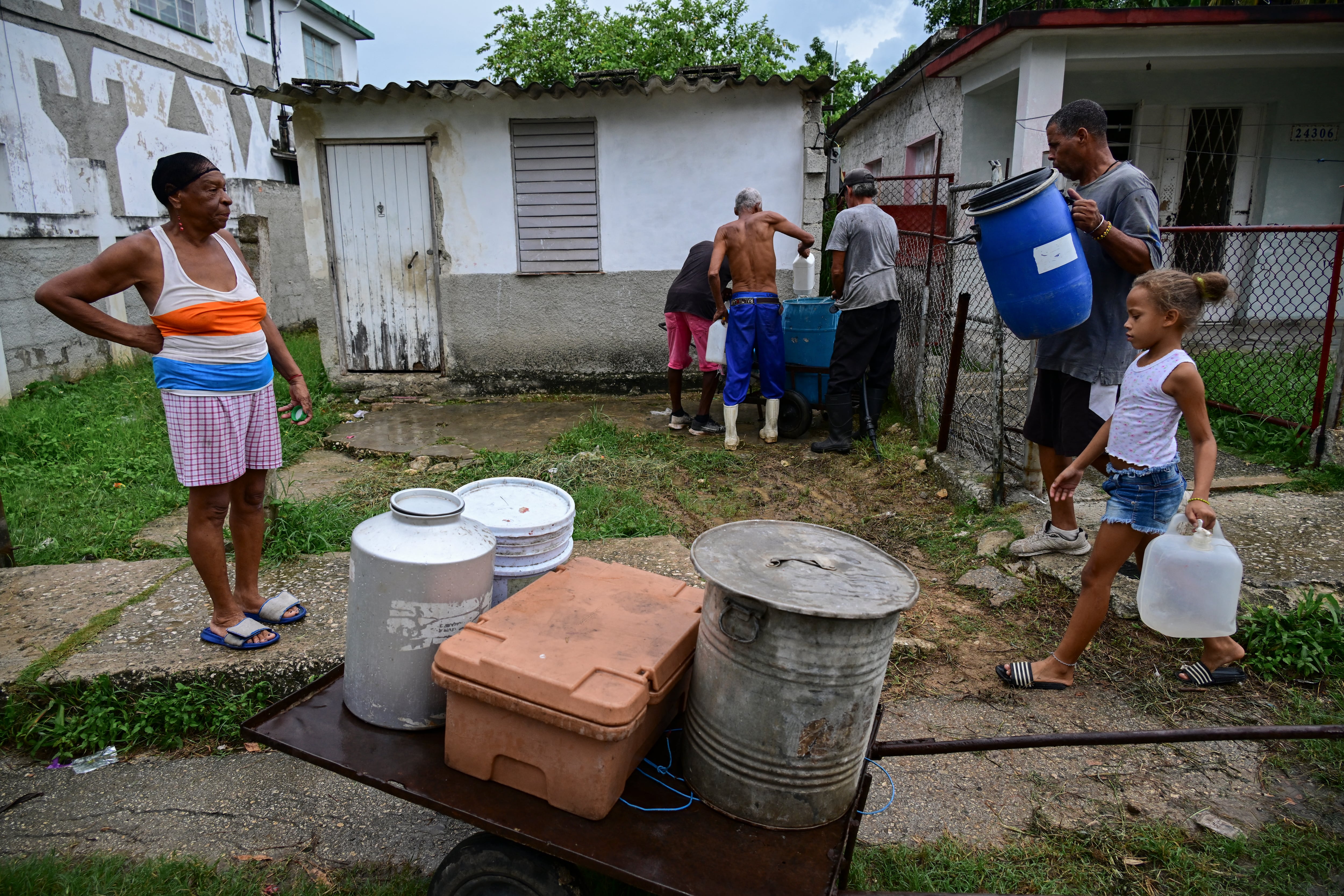 People fill buckets and containers with water along a street in Punta Brava, west of Havana, on September 16, 2026. (Photo by YAMIL LAGE / AFP)