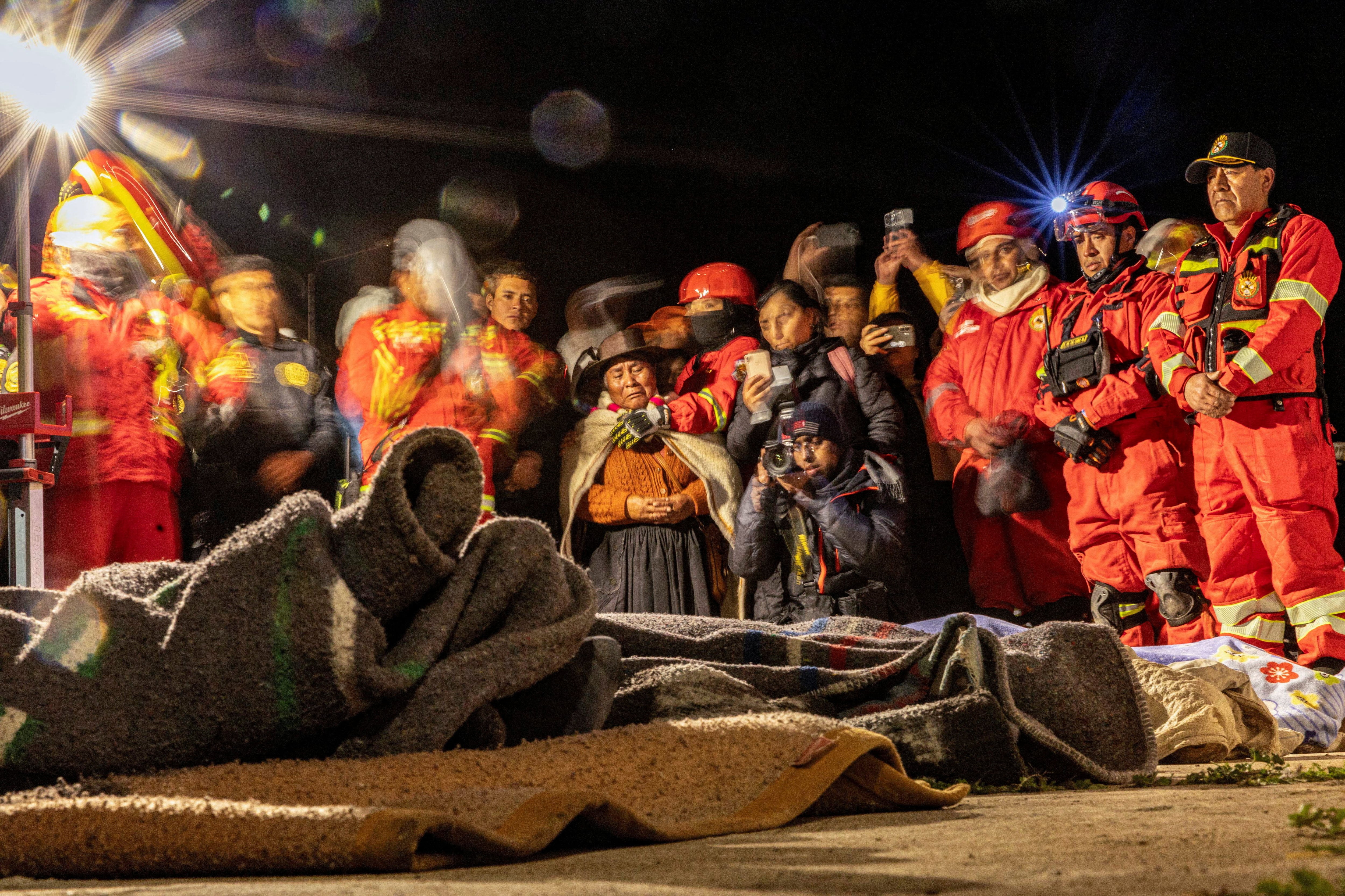 Varias personas rezan junto a los cuerpos de cuatro víctimas del terremoto de magnitud 5,6 que sacudió el centro de Perú el sábado, en Chupuro (Perú), el 19 de julio de 2026. Fotografía tomada con exposición prolongada. REUTERS/Yershon Vilca