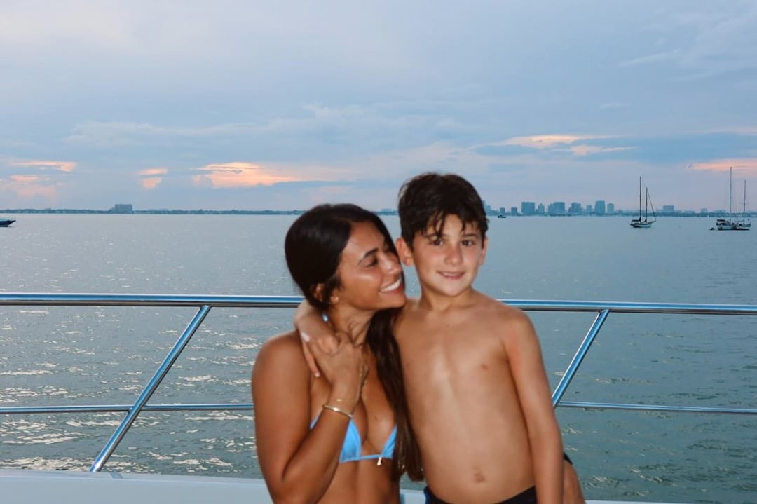 Antonela Roccuzzo y uno de sus hijos posan abrazados en la cubierta de un yate al atardecer