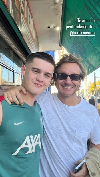 Dos hombres sonrientes, Benjamín Vicuña con gafas de sol y camiseta blanca abraza a Bautista Vicuña, quien viste una camiseta deportiva verde