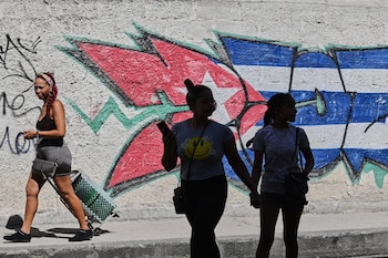 Varias personas pasan junto a grafitis con los colores de la bandera cubana en La Habana, Cuba, el miércoles 17 de junio de 2026 (Foto AP/Jorge Luis Baños)