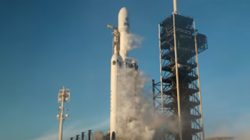Cohete blanco con el logotipo de SpaceX y el emblema de la NASA junto a una torre metálica en una plataforma con vapor bajo el cielo azul
