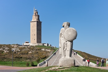 En un monte, la torre de fondo y Breogán en primer plano.