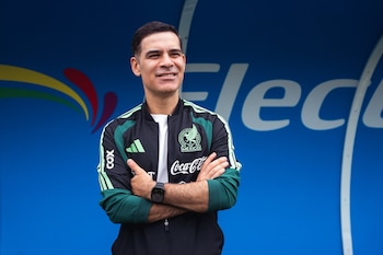 Rafael Márquez viste una chaqueta deportiva verde y negra con el escudo de México y permanece de brazos cruzados frente a un fondo azul