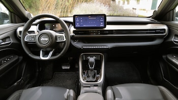 Interior de un automóvil con volante, panel de instrumentos digital, pantalla táctil multimedia y consola con palanca de cambios
