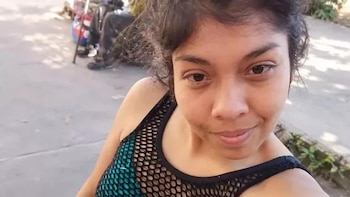 Primer plano de una mujer de cabello oscuro y camiseta de red en un espacio al aire libre