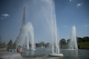 Personas se refrescan en la fuente del Trocadero frente a la Torre Eiffel durante la ola de calor en Francia. (Julien de Rosa/AFP)
