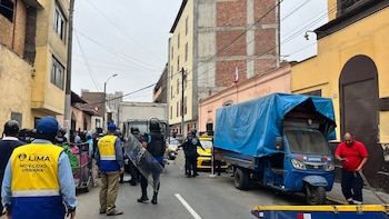 Inspectores con chalecos amarillos y agentes con escudos se encuentran junto a un motofurgón azul cubierto con una lona en una calle