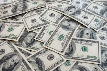 Múltiples billetes de cien dólares de Estados Unidos colocados de forma desordenada unos sobre otros.