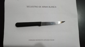 Un cuchillo con mango negro sobre un papel blanco con las frases SECUESTRO DE ARMA BLANCA y COMISARIA MORON 4TA GERVASIO PAVON