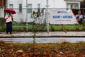 Imagen de archivo de una mujer esperando un autobús junto a un letrero del Servicio Postal de Estados Unidos que dice "estamos contratando" en Boston, Massachusetts, Estados Unidos. 30 de octubre, 2021. REUTERS/Brian Snyder/Archivo