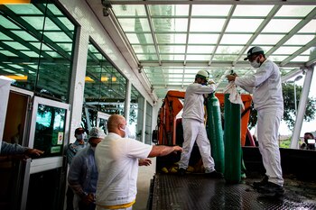 Varios hombres cargan unos cilindros