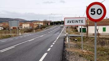 Carretera, señal de entrada al pueblo de Aveinte, señal de límite de velocidad 50, coche blanco, casas, árboles, montañas, cielo nublado.