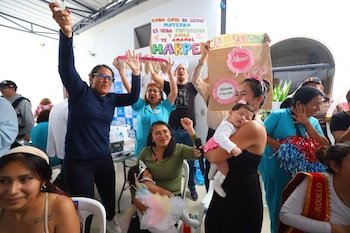Varias mujeres sostienen bebés en brazos y muestran carteles con mensajes sobre la lactancia materna durante un evento público