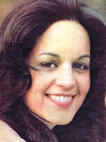 Primer plano de Lady M con cabello oscuro y largo, ojos marrones, y una sonrisa que muestra dientes blancos. Su rostro está bien iluminado