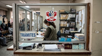 Ventanilla de vidrio con el logotipo del Jurado Nacional de Elecciones, un cartel de trámites, pasaportes, documentos y una trabajadora.