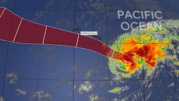 Mapa satelital del Océano Pacífico con un sistema meteorológico de colores intensos, una franja roja que indica su trayectoria y la ciudad de Honolulu