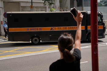 Una mujer hace un gesto hacia un vehículo del servicio penitenciario tras la condena del activista Joshua Wong por participar en una manifestación no autorizada, en Hong Kong (REUTERS/Lam Yik)