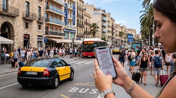 Una persona sostiene un teléfono con una alerta en pantalla, frente a una calle con un taxi, un autobús y peatones con equipaje.
