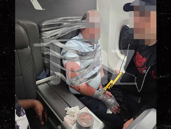 Hombre sentado en el interior de un avión con cinta adhesiva gris alrededor del torso, la cabeza y las manos