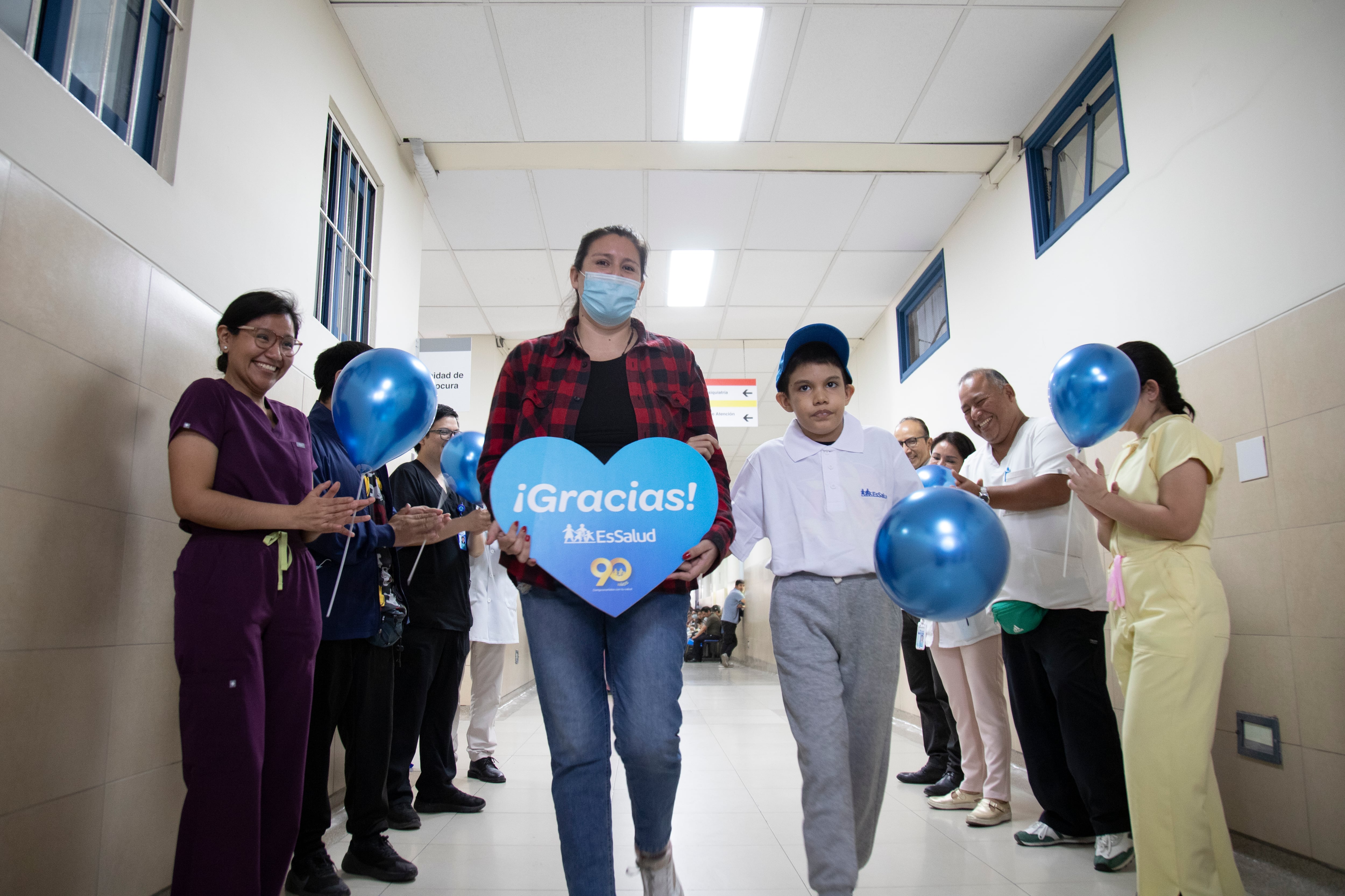 Un niño y su madre caminan entre los aplausos del personal médico de EsSalud tras una cirugía de reconstrucción esofágica que le permite volver a comer. (EsSalud)
