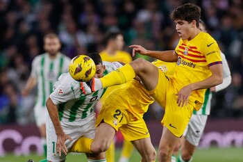 El defensa del FC Barcelona, Pau Cubarsi (d), despeja el balón ante el delantero brasileño del Betis, Willian José, durante el encuentro correpondiente a la jornada 21 de Primera División que Betis y FC Barcelona disputaron en el estadio Benito Villamarín, en Sevilla. EFE/José Manuel Vidal.