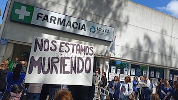 Un grupo de personas frente a una farmacia con el letrero de IOSFA y una pancarta en primer plano con el texto «Nos estamos muriendo»