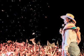 Keiko Fujimori, vestida con sombrero y un chal colorido, sonríe al hablar por un micrófono en un escenario iluminado, frente a una multitud en un mitin nocturno con confeti en el aire