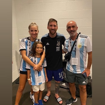 Lionel Messi, Residente, Soledad Fandiño y un niño posan sonrientes. Todos llevan camisetas de Argentina y credenciales de acceso. Fondo de pared blanca