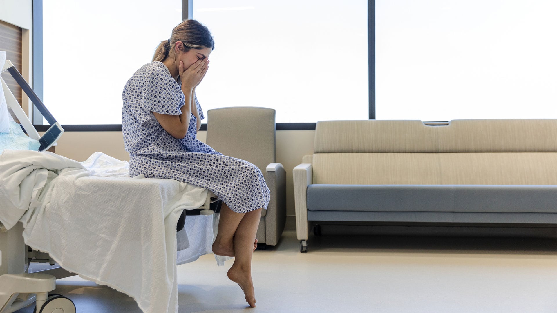The young adult woman holds her face and cries after receiving some devastating news about her lab results. (Getty)