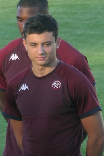 Louis Bielle-Biarrey, joven jugador de rugby con camiseta granate de Union Bordeaux Bègles con logos Kappa y del club, sobre césped verde