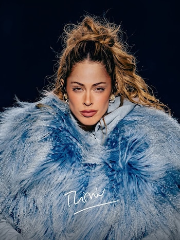 Retrato de Tini con abrigo celeste de pelo sintético, peinado alto y su firma escrita en la parte inferior