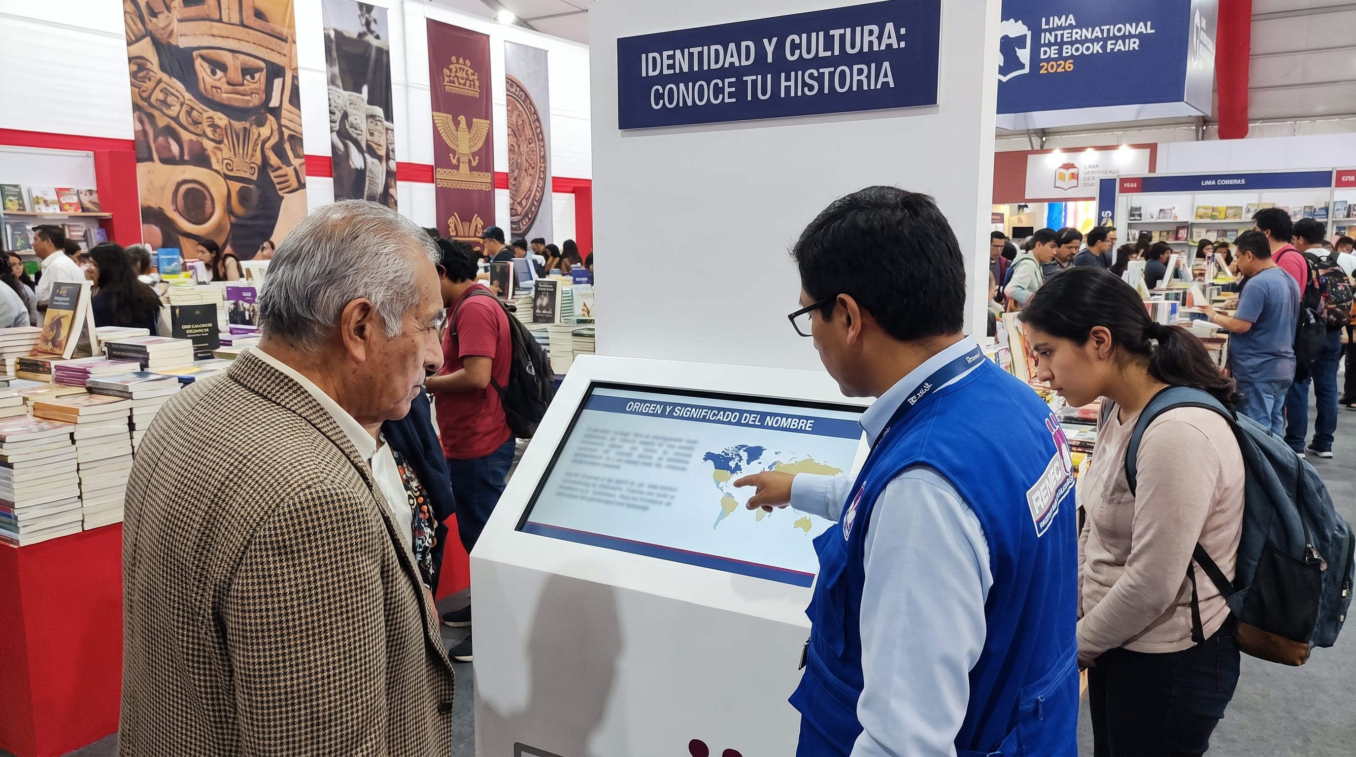Un visitante consulta el origen y significado de su nombre en un módulo interactivo del Reniec, que un orientador explica durante la Feria Internacional del Libro de Lima 2026. (Imagen Ilustrativa Infobae)