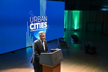 Un hombre en traje habla desde un atril con el logo de Buenos Aires frente a una gran pantalla azul con la frase Urban Cities