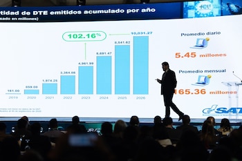 Un hombre en traje habla desde un atril junto a una pantalla azul que dice Factura Electrónica Summit 2026 frente a un público sentado