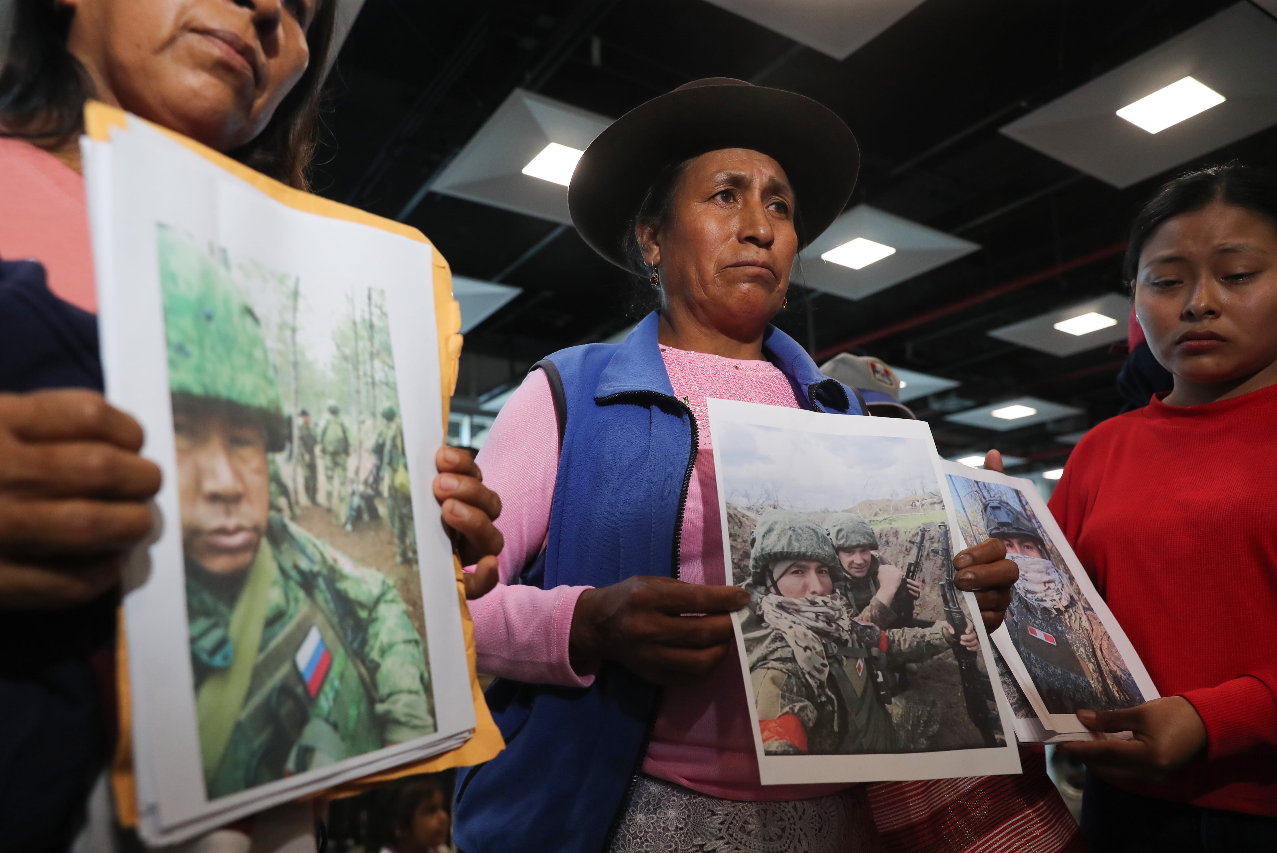 Familiares de peruanos reclutados por Rusia para la guerra contra Ucrania fueron captados este 4 de mayo al sostener fotografías de sus allegados, en el aeropuerto internacional Jorge Chávez, cerca a Lima (Perú). EFE/Paolo Aguilar