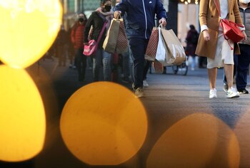Passanten gehen mit Einkaufstüten hinter